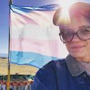 A photo of [Erika Hodges] beside the trans flag