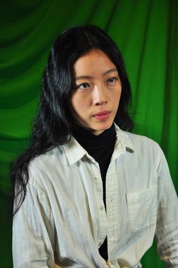 Photo of Mindy Seu in front of a green background.