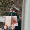 A photo of a person holding a book, their face hidden behind it 