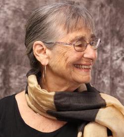 Alicia Ostriker smiles, wearing a striped scarf.