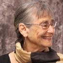 Alicia Ostriker smiles, wearing a striped scarf.