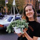 A photo of [Louise] holding a potted green plant. 