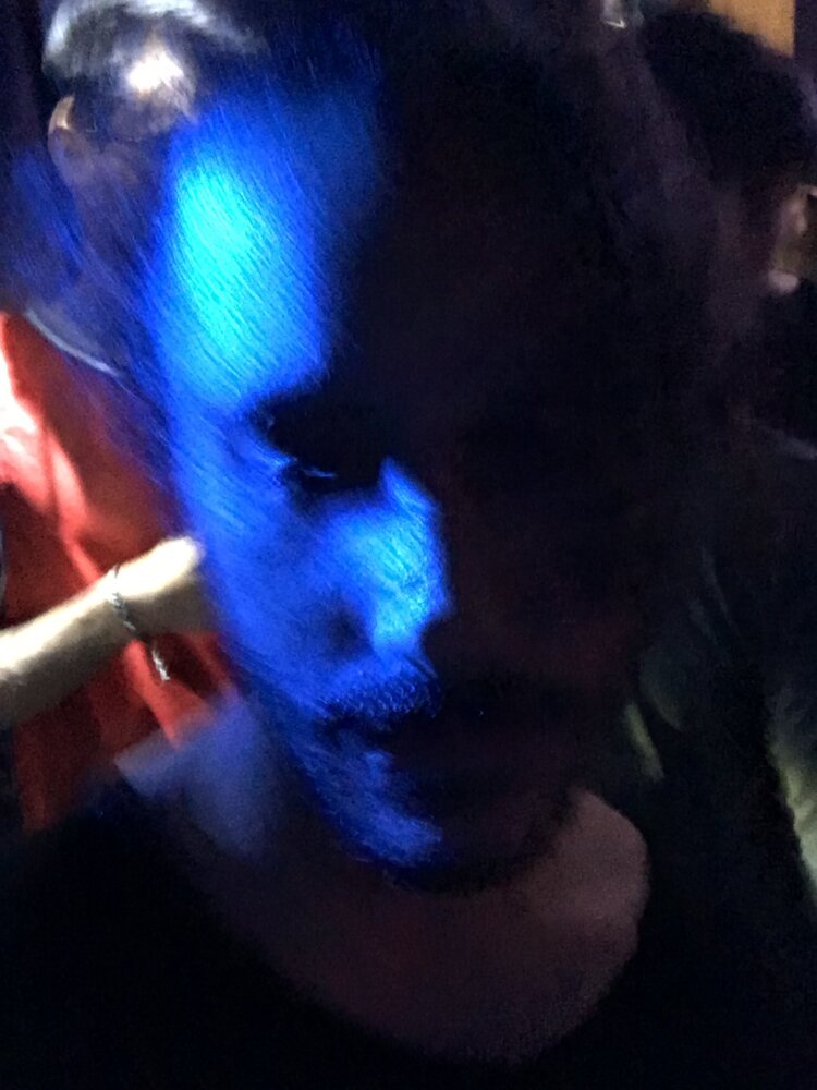 A photo of poet benjamin krusling in blurred, bluish light.