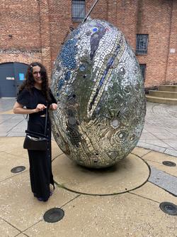 A photo of Claire in front of a large silver egg-like sculpture