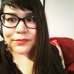A photo of poet Casandra López on a red couch. A photo of poet Casandra López on a red couch.