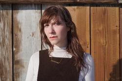 A photo of Elaine Kahn in front of wooden panels 