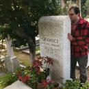 A photo of [Ian Dreiblatt] kissing a gravestone.