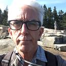 A photo of Steve Benson in front of rocks, trees, and sky.