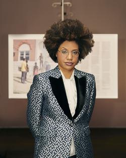 A photographic portrait of the artist LaToya Ruby Frazier wearing a silver suit. 