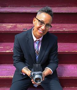 Photo of Lola Flash sitting on pink steps and holding a camera