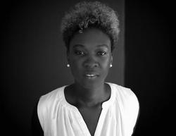 A black and white photograph of Canisia Lubrin, wearing a white shirt and earrings.