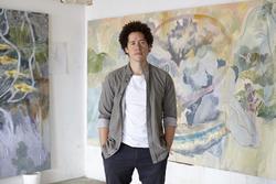 Photo of Michael Armitage in front of his paintings