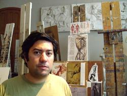 A photo of poet Carlos Soto-Román in front of easels and anatomical drawings.