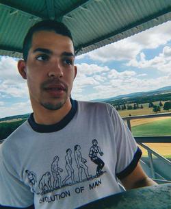 A photograph of poet Dagan Brown wearing an "evolution of man" shirt.