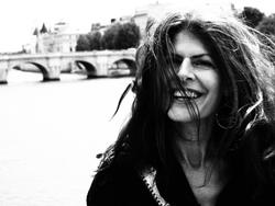 A black and white photo of poet Eleni Sikelianos smiling at Pont des Arts.