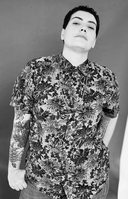 A black and white photo of poet Raquel Salas Rivera in a printed button up.