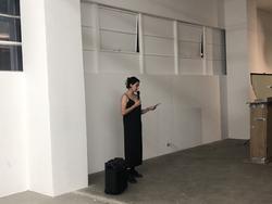 A photo of Sarah Yanni reading in front of a white wall