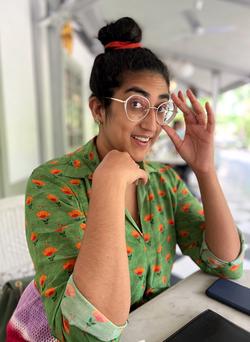 A photo of Tara Jayakar in glasses and a colorful shirt 